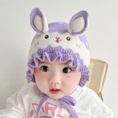 Smiling baby showcasing a sweet rabbit winter hat, an adorable addition to kids apparel.