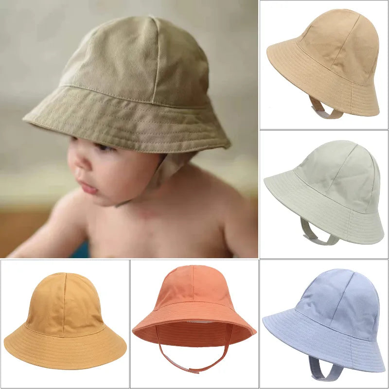 Adorable baby in adjustable pink sun protection bucket hat, playing outdoors with a smile.