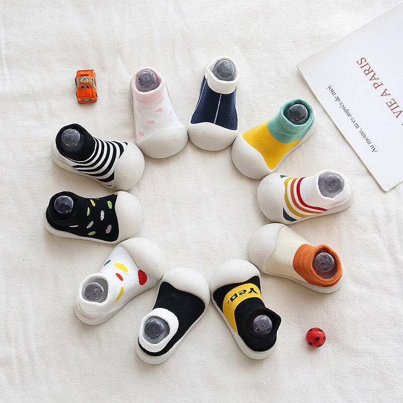 Closeup of baby's multicolor cotton booties, featuring a non-slip soft sole for new walkers.