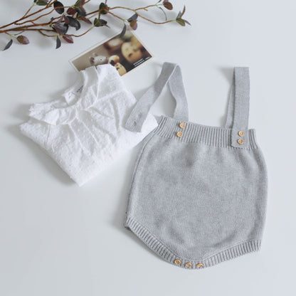 Studio shot of a hand-knitted warm wool baby romper folded, ready as a newborn outfit.