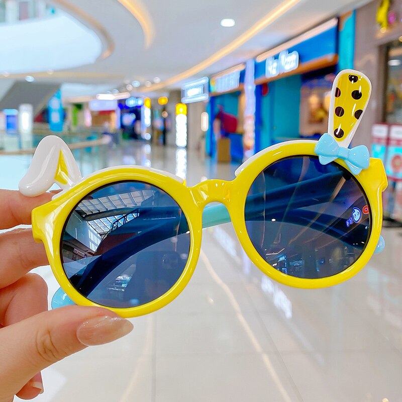 Vibrant yellow duck cartoon sunglasses for girls, emphasizing kids eyewear and UV defense.