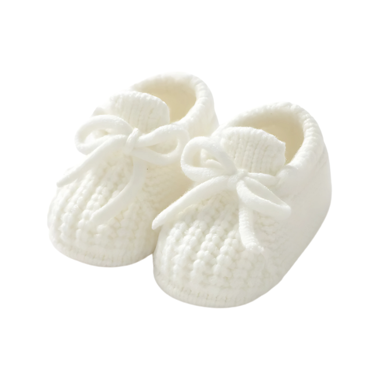 A pair of yellow baby knit booties on a wooden surface, essential and gentle baby footwear.