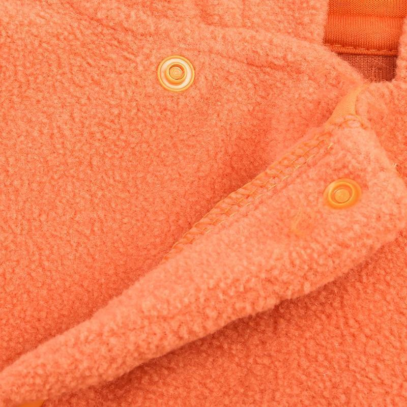 Close-up of a festive orange pumpkin onesie for infants, showing soft fleece texture.