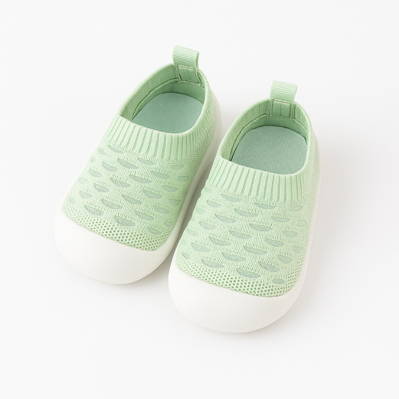 Baby girl wearing pink knit first walking shoes for comfort and support.