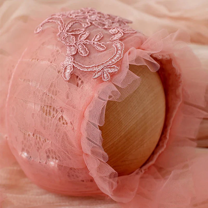 Close-up of the delicate floral lace and soft mesh on a pink baby girl's romper set.