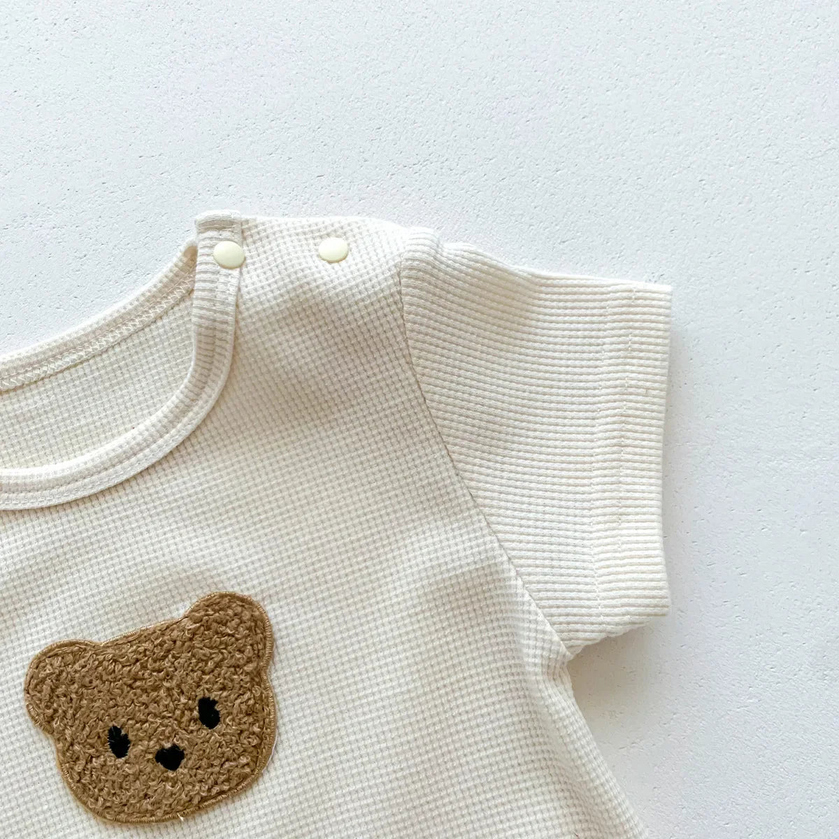Infant playing softly while wearing the comfortable bear themed newborn romper.