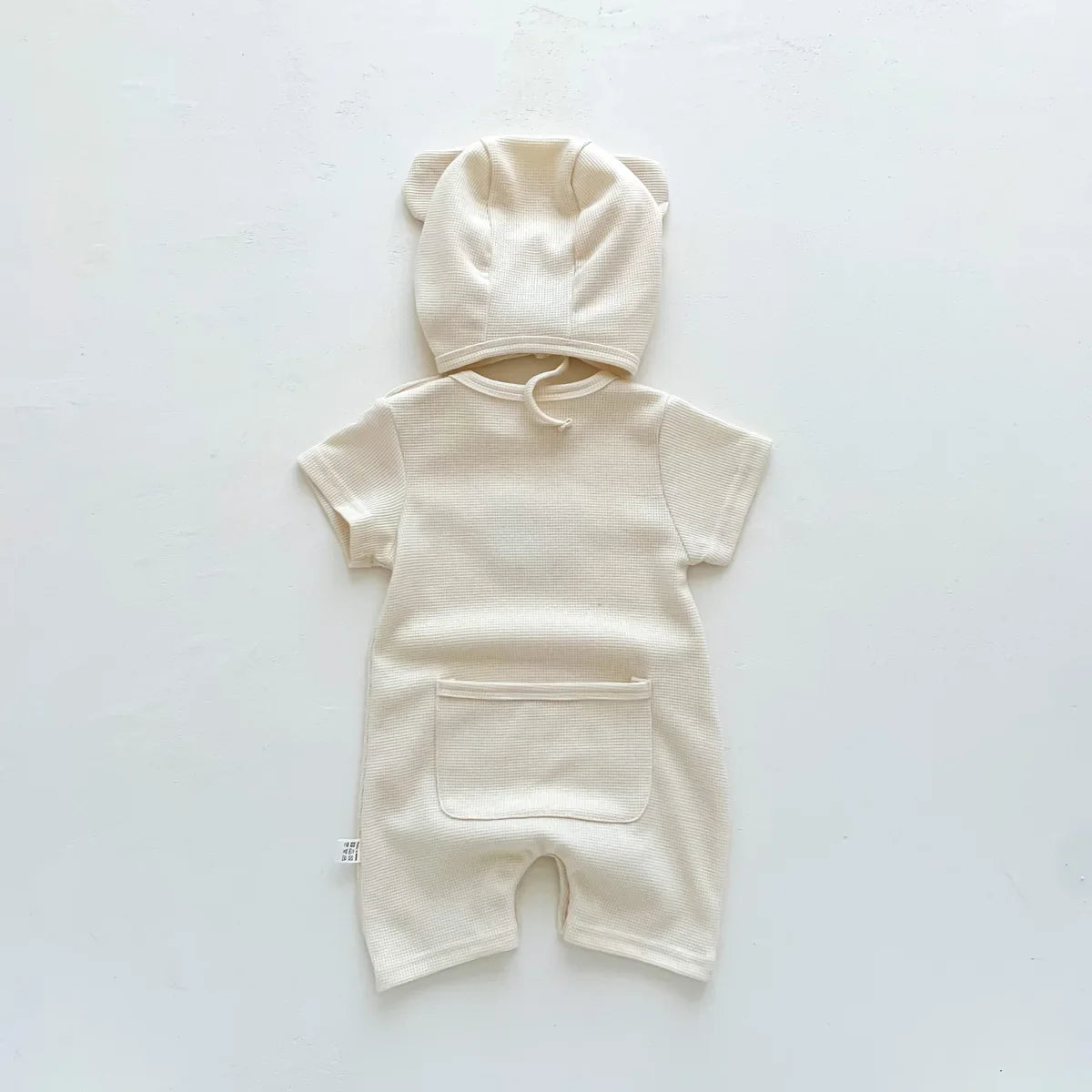 Happy newborn in a cute bear romper, capturing the joy of infant fashion.