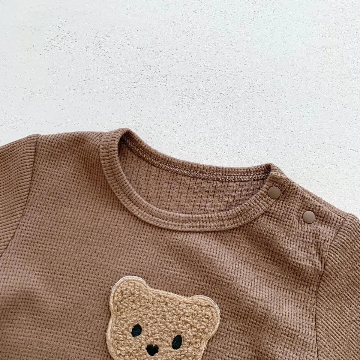 Collection of newborn bear rompers in various pastel colors, unisex baby clothes.