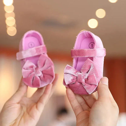 Close-up of a baby girl's first walker bow flat shoe in light pink, cotton, anti-slip sole