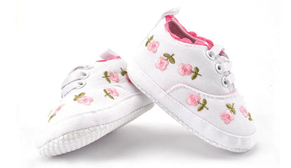 Adorable pink baby girl's first walker shoes with delicate lace floral details, perfect for infants.