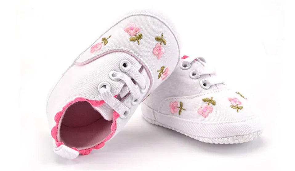 Pink baby girl's shoes with charming lace floral accents, ideal for first steps and baby fashion.