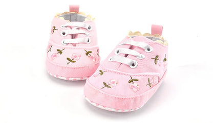 Navy lace floral infant footwear, perfect for baby girls learning to walk. Soft cotton first walkers.