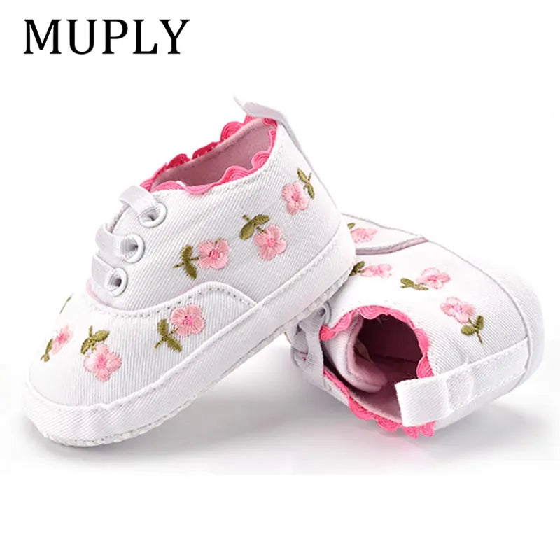 Close-up of the intricate lace floral design on pink baby girl's first walker shoes, soft and stylish.