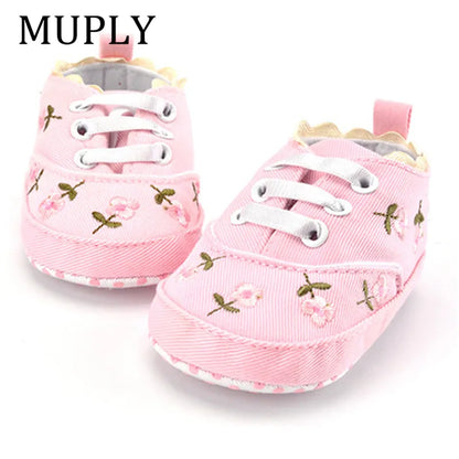 Baby girl in white lace floral first walker shoes, standing on a soft rug, ideal infant footwear.
