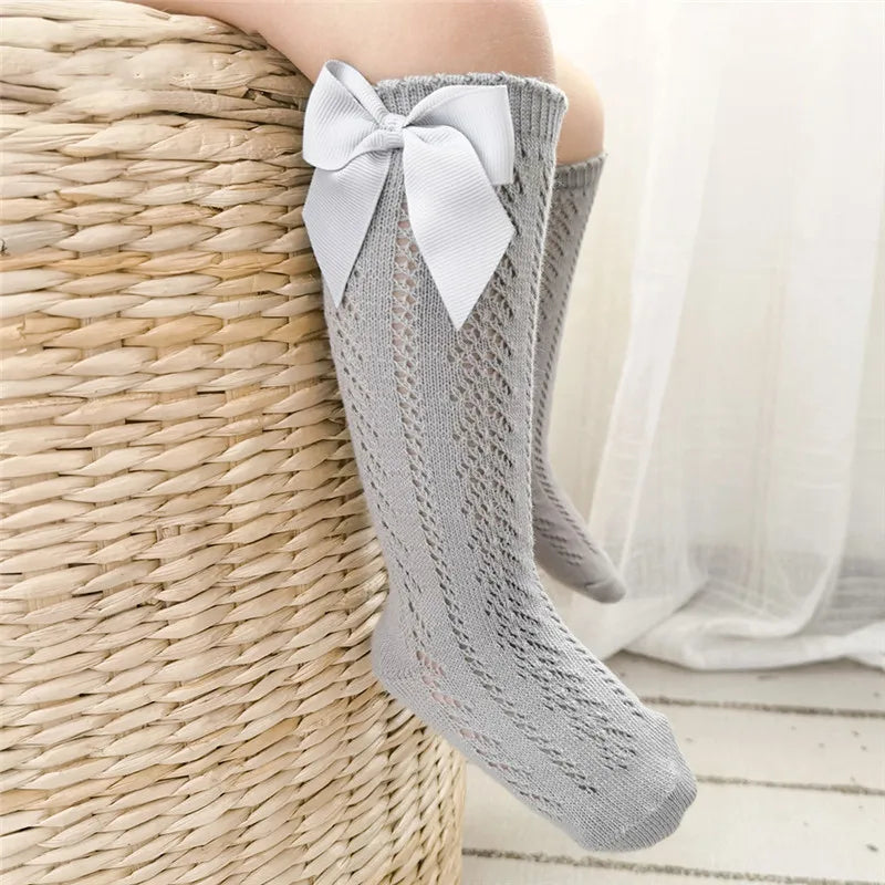 Stylish cream knee-high bow socks for children, a versatile accessory.