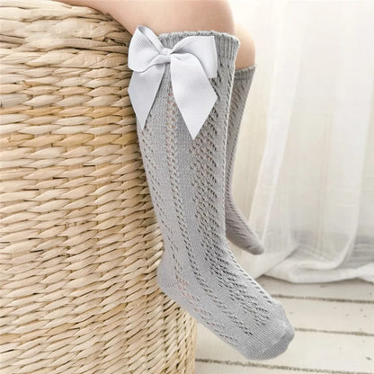 Stylish cream knee-high bow socks for children, a versatile accessory.
