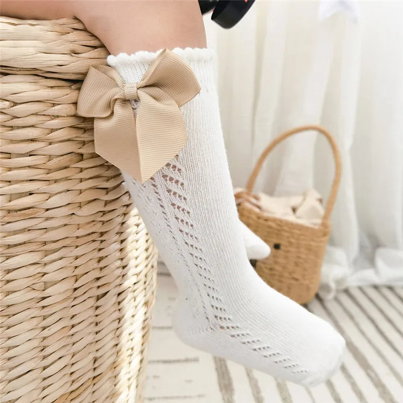 Cute white knee-high socks with bows for children, comfortable and stylish.