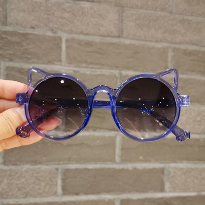 Young girl happily wearing blue cartoon cat eye sunglasses, UV protection, children's fashion accessory