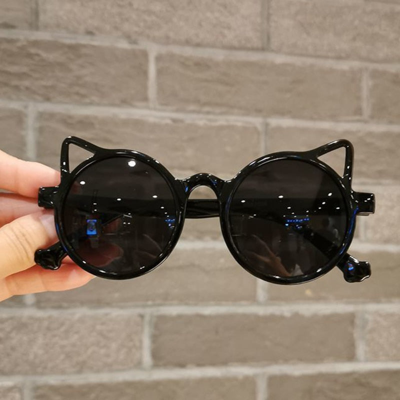 Side view of pink cartoon cat eye sunglasses on a flat surface, UV protection, toddler eyewear