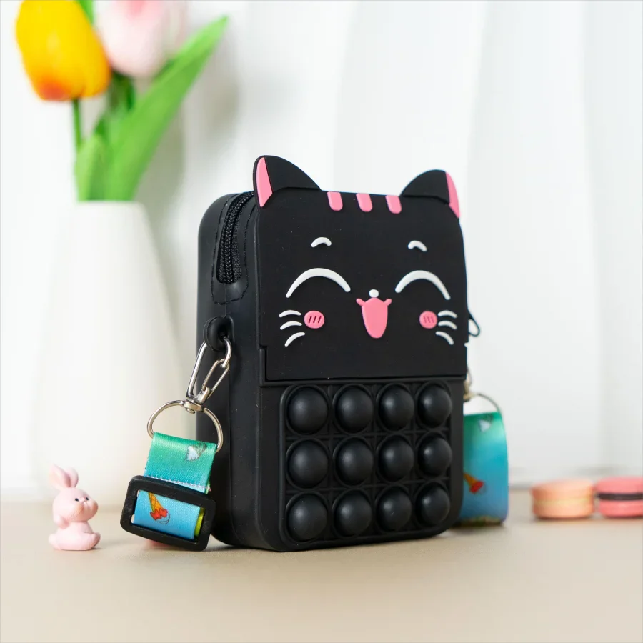 Child's hand holding a blue cat silicone coin purse, easy to grip design.