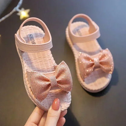 Close-up of a pink girls' bow sandal, showing textured non-slip sole & soft straps