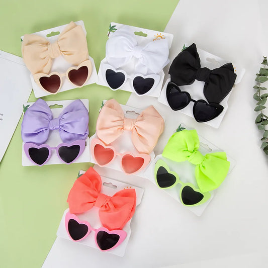 Adorable pink heart sunglasses with a matching pink bow headband for toddlers, perfect baby fashion accessory.