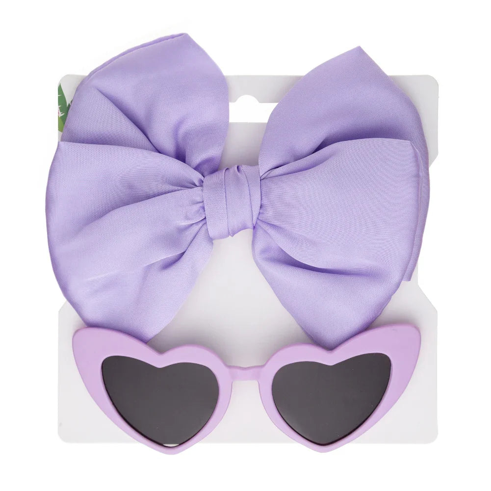 Vibrant pink heart sunglasses with UV protection and a soft, comfortable bow headband for kids.