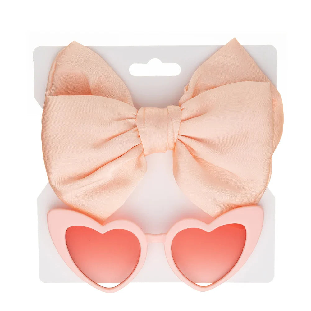 Cute children's gift set featuring pink heart sunglasses and a matching bow headband, ideal for toddlers.