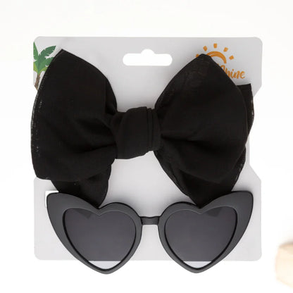 Child enjoying playtime while wearing the pink heart sunglasses and a coordinated bow headband.