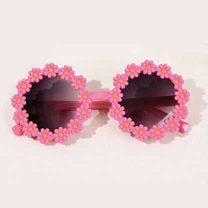 Happy child wearing pink UV protection sunglasses and a matching bow headband.
