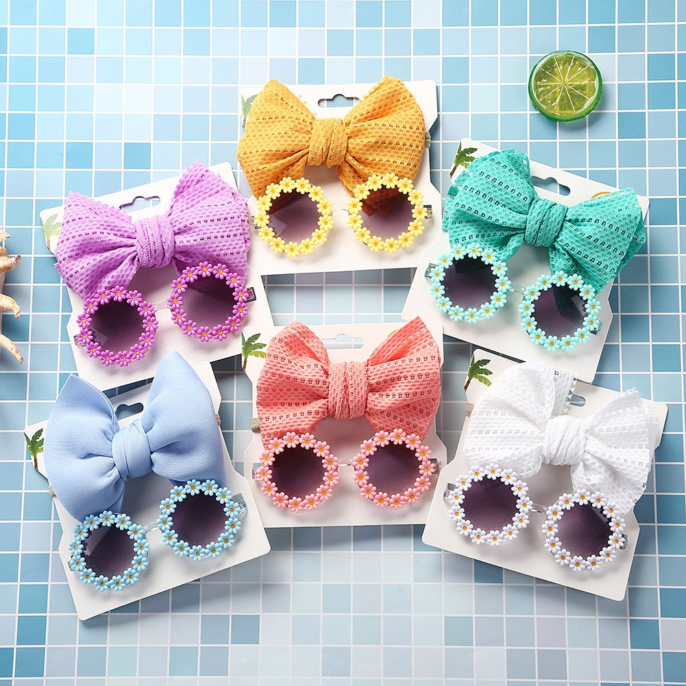 Set of pink kids' UV protection sunglasses and a bow headband on a white background.