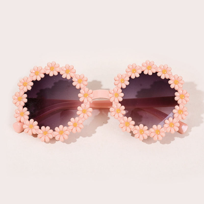 Pink kids' sunglasses with heart frames and a matching bow headband, sun protection fashion.