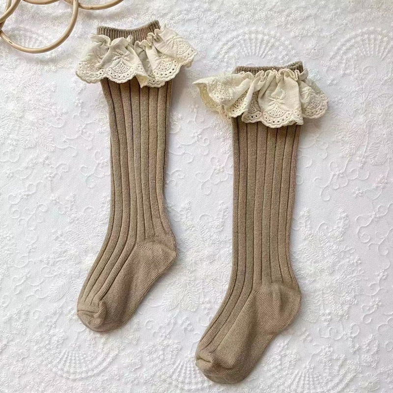Close-up of white cotton girls' socks with delicate lace and flower embellishments