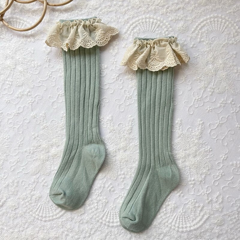 Green cotton infant sock featuring delicate lace, a frill, and a charming floral design