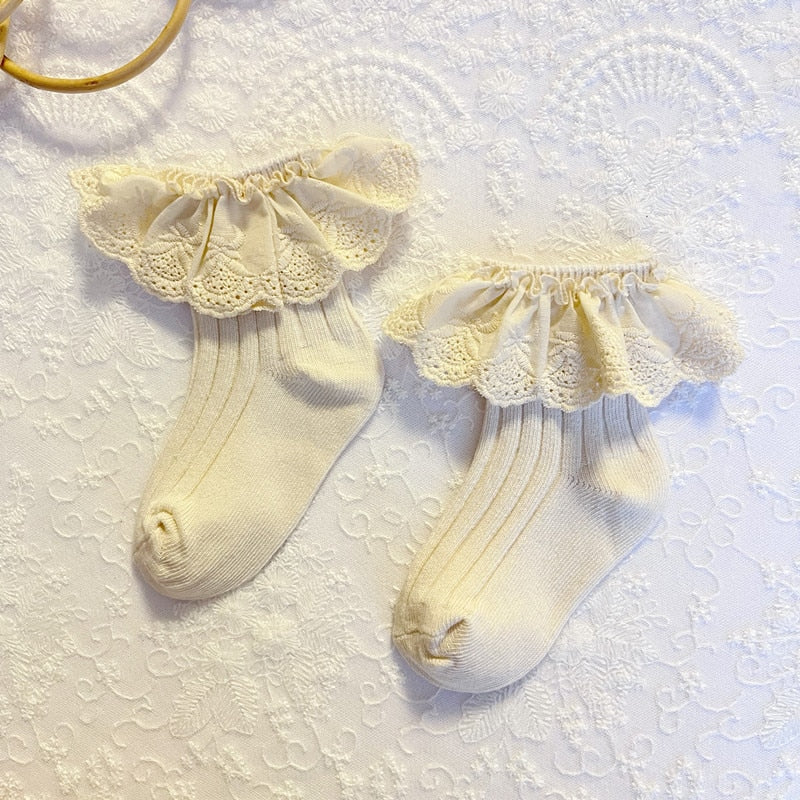 Baby girl wearing white lace frilly flower cotton socks, showing cute infant footwear