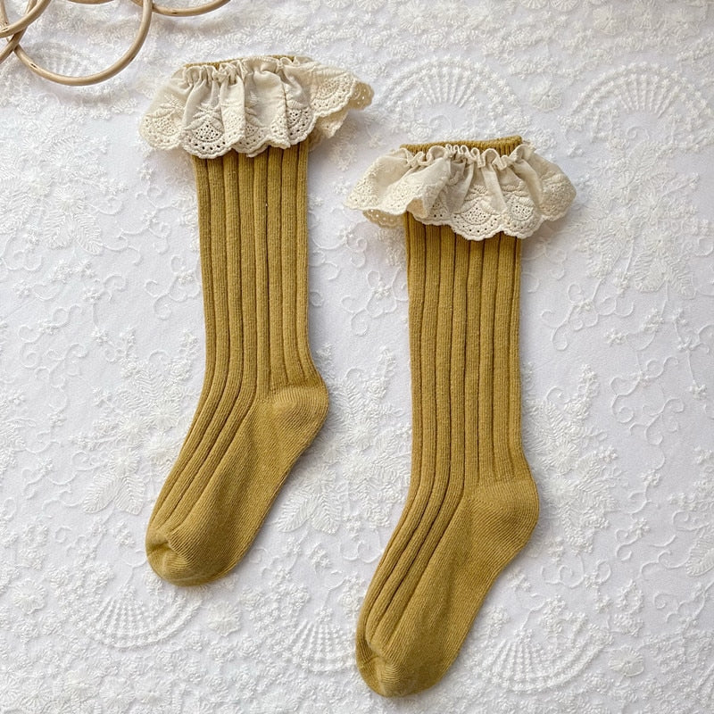 Detailed view of the frilly lace and embroidered flower on a pink cotton baby sock