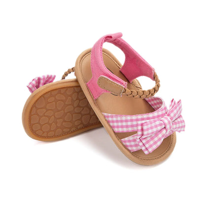 Close-up of the princess bow detail on pink toddler sandals, comfortable baby footwear.