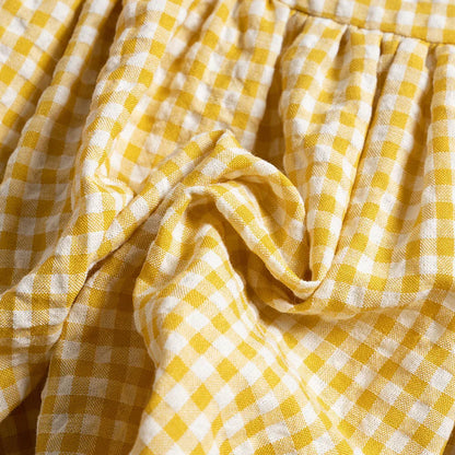 Infant girl playing happily in a comfortable plaid cotton romper dress, summer ready outfit