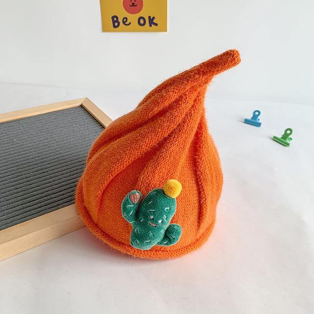 Hand holding a small red knit gnome beanie, emphasizing its cozy texture and quality.