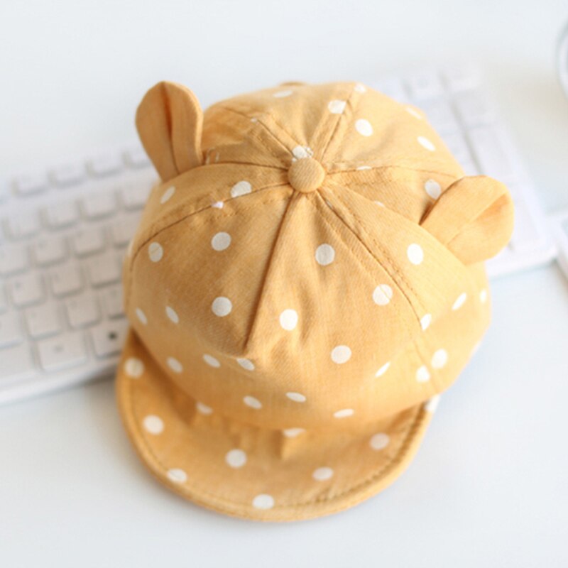 Baby's headwear: green polka dot cotton sun hat, offering sun protection for active toddlers.