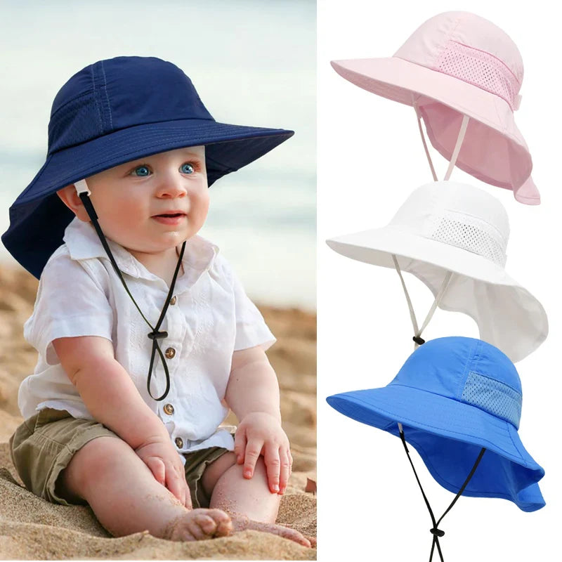 Adorable toddler wearing a blue adjustable sun protection bucket hat on a sunny beach, smiling sweetly.