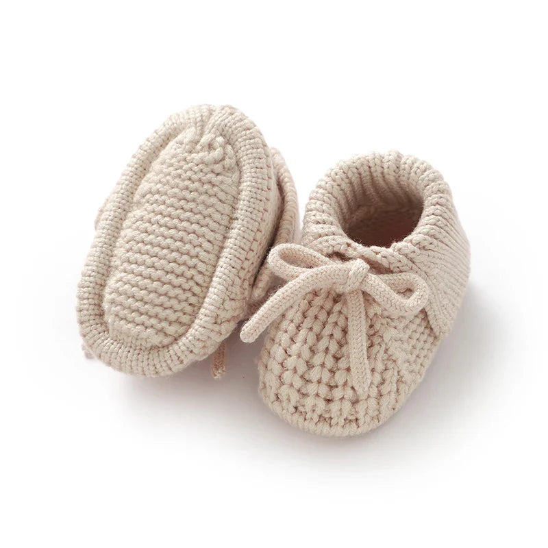 Close-up of grey knitted baby booties with button detail, soft sole crib shoes, ideal baby shower gift