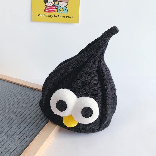 Happy child wearing a yellow googly eyes beanie, demonstrating its cute kidswear appeal.