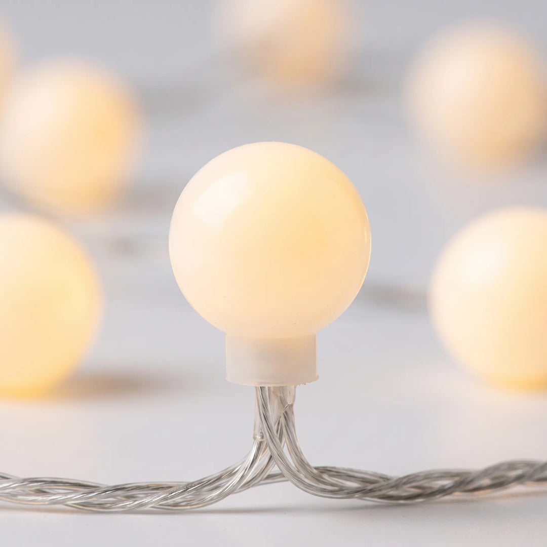 Decorative fairy globe LED string lights draped in a bedroom, providing soft, ambient mood lighting for cozy decor.