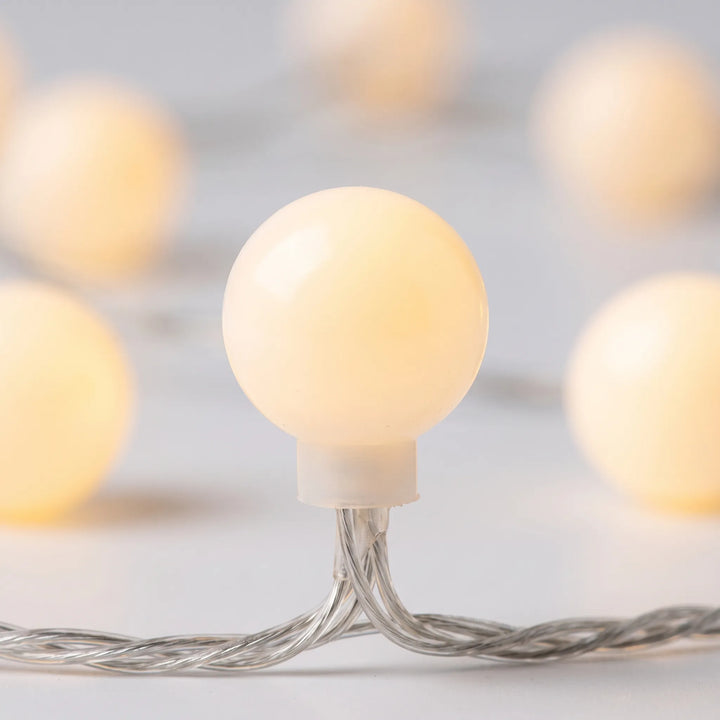 Decorative fairy globe LED string lights draped in a bedroom, providing soft, ambient mood lighting for cozy decor.