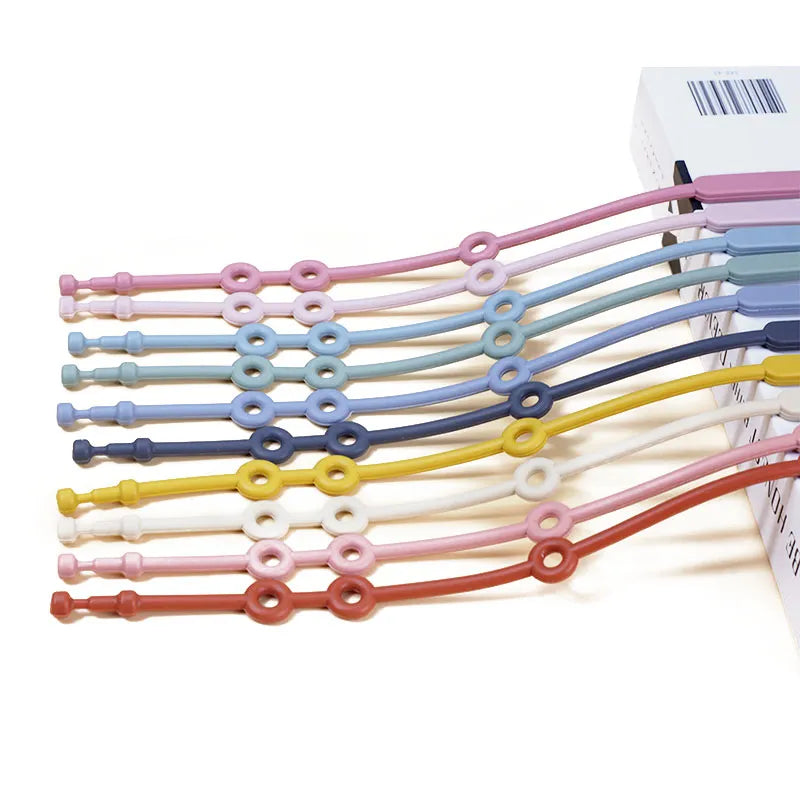 Green adjustable silicone toy strap tethering a teething toy to a stroller bar for infants.