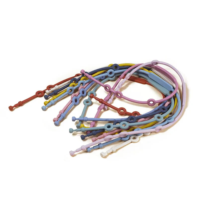 Infant playing with a toy attached by a purple adjustable silicone safety strap to a car seat.