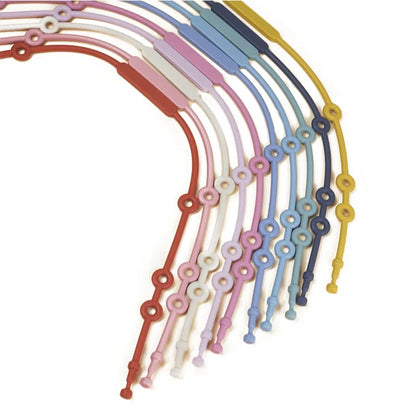 Yellow adjustable silicone toy holder wrapped around a crib rail, keeping a toy within reach.