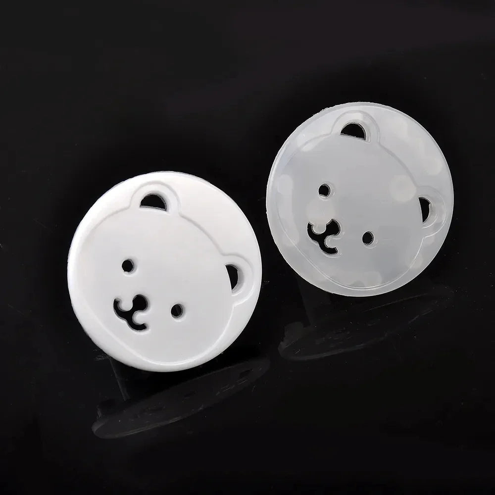 Stack of 10 white baby bear socket covers, emphasizing their child safety and electrical protection role.