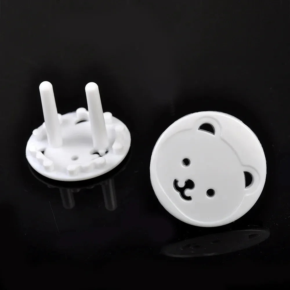 Hand demonstrating installation of a white bear socket cover onto an electrical outlet for child safety.
